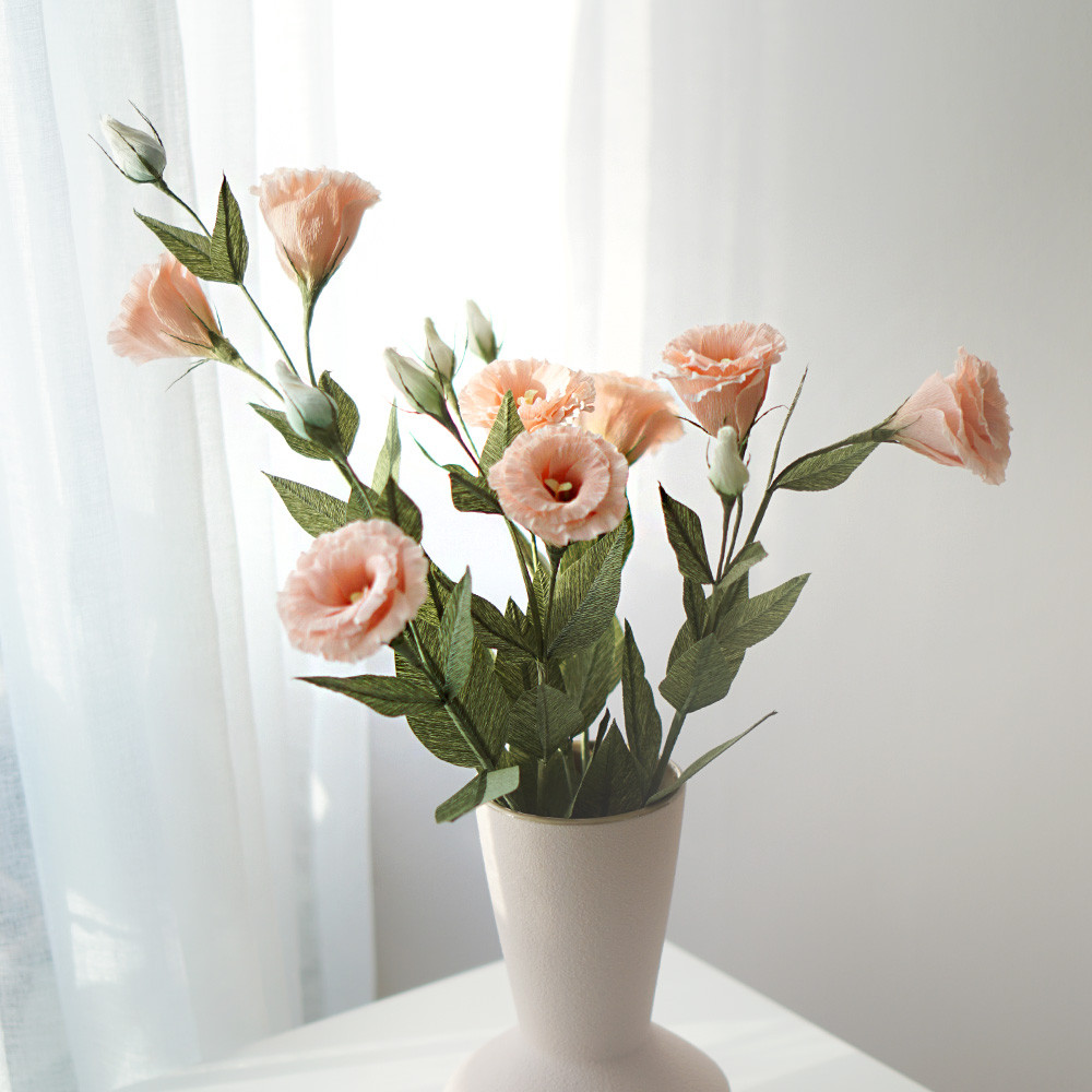 Pink crepe paper lisianthus flowers in a white vase by a window