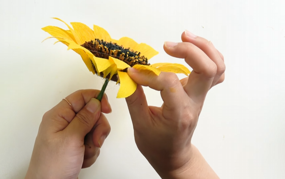 Attaching green crepe paper sepals underneath the sunflower