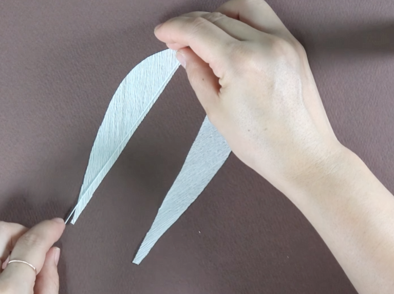 Attaching floral wire to green crepe paper with hot glue for lily leaves