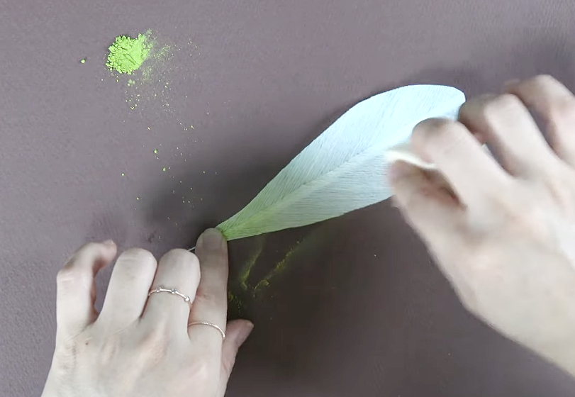 Cutting a lily leaf shape from green crepe paper using a paper template