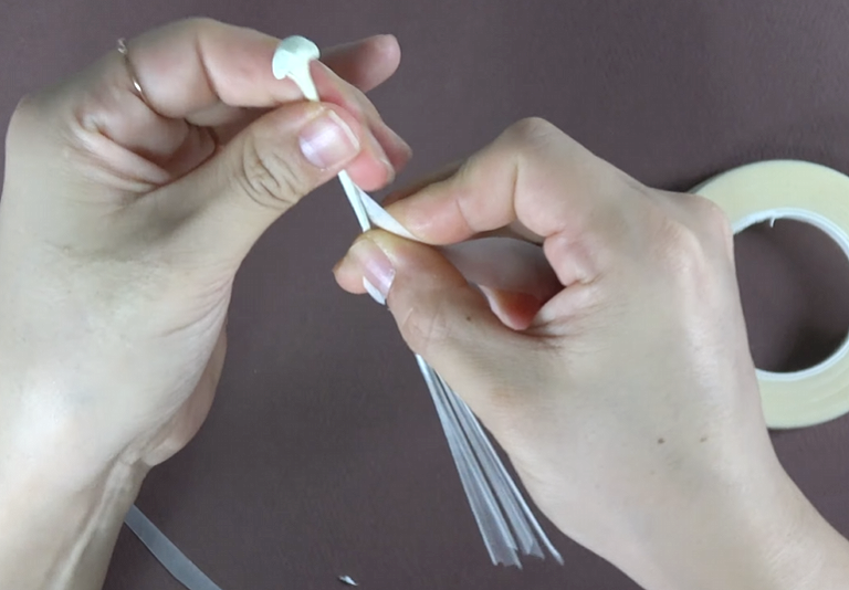 Gently stretching and shaping white crepe paper petals for a realistic lily