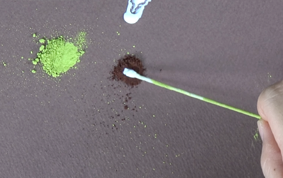 Adding light green pastel powder to the base of a white crepe paper lily petal