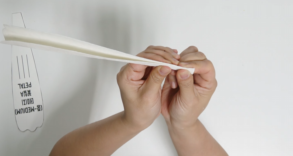 Shaping a giant daisy petal by bending the wired crepe paper
