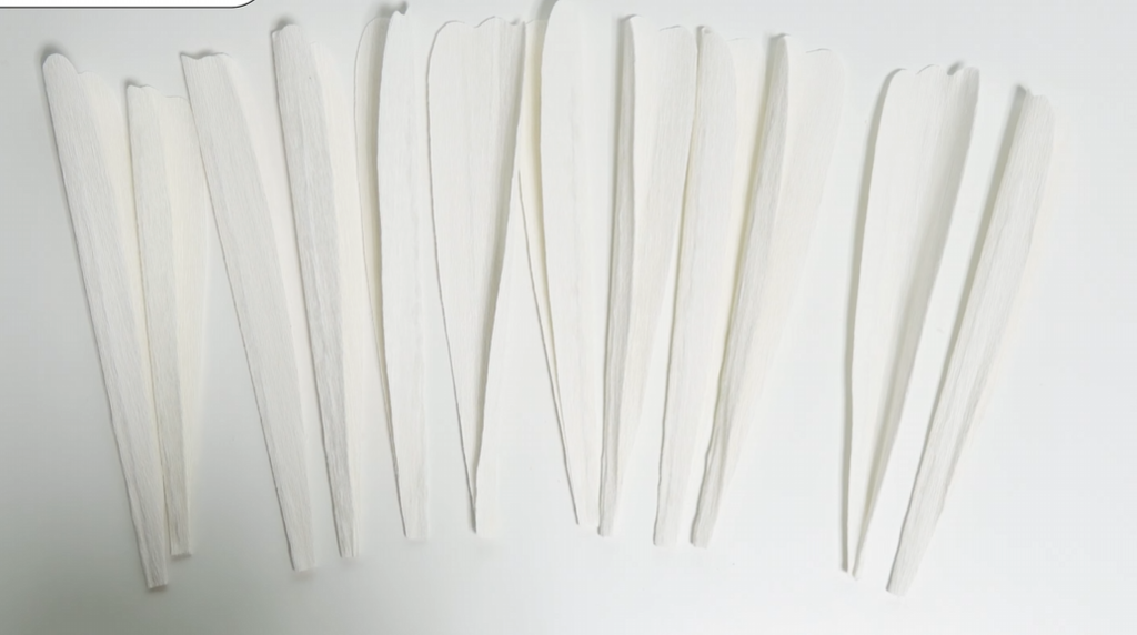 Cut white crepe paper petals for a giant daisy arranged before shaping
