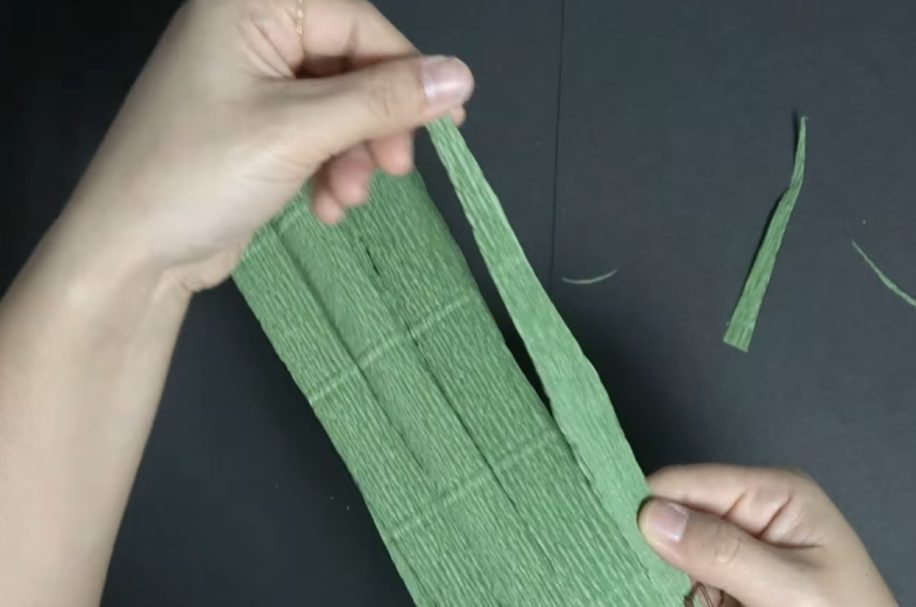 Cutting green crepe paper to prepare leaves for a giant daisy