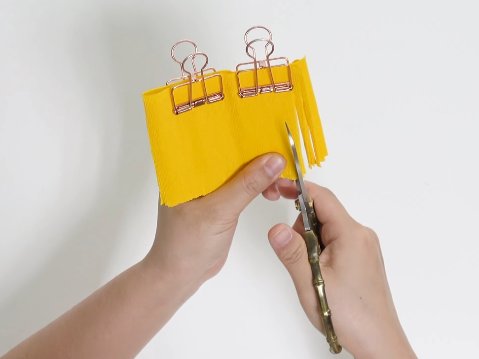 Cutting yellow crepe paper into fine fringe for a giant daisy center
