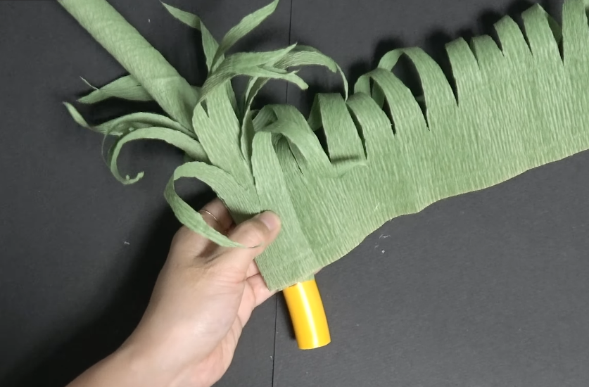 Wrapping curled green crepe paper grass around the base of a giant daisy stem