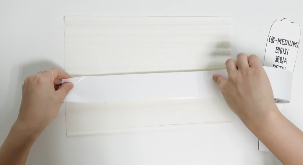 Applying hot glue to white crepe paper for giant daisy petals