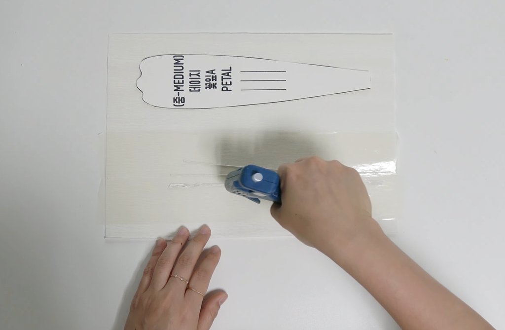 Applying double-sided tape to white crepe paper for giant daisy petals