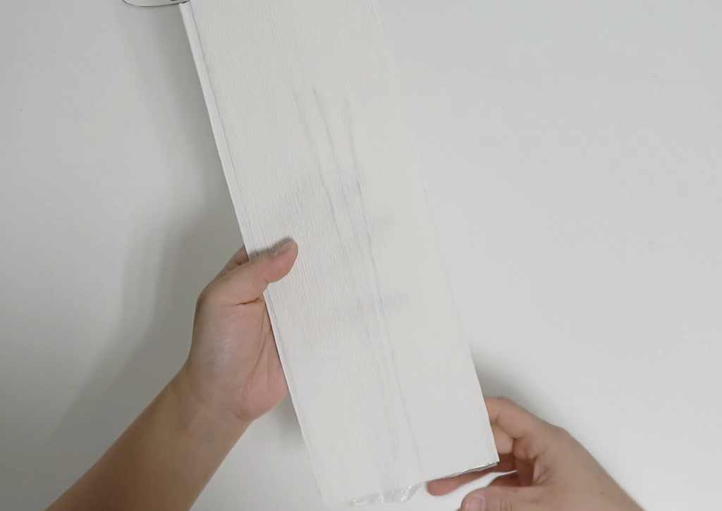 Folding white crepe paper over floral wires to make giant daisy petals
