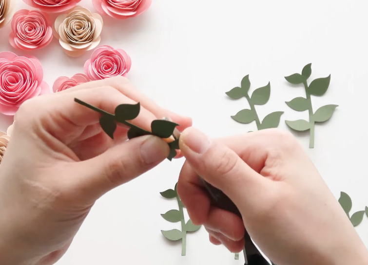 Curling green paper leaves with scissors for a paper flower arrangement