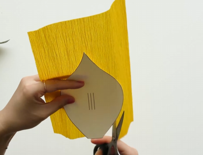 Cutting yellow crepe paper with a petal pattern for a paper calla lily