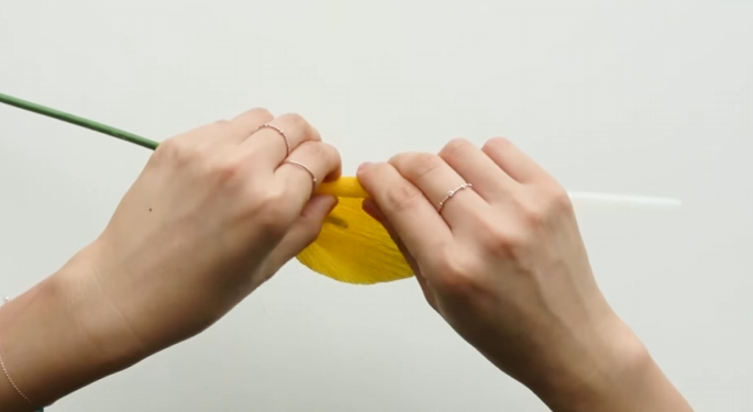 Curling the edge of a yellow crepe paper calla lily petal with a glue stick