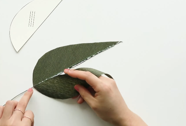 Attaching green paper-covered wire between two crepe paper calla lily leaf pieces