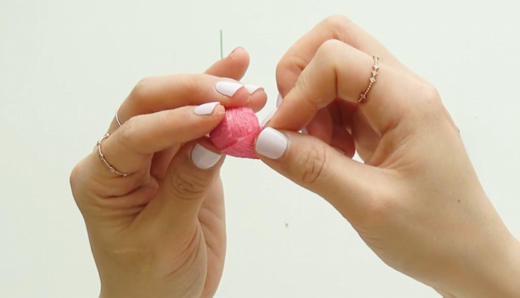 Covering a Styrofoam ball with pink crepe paper to form a flower bud