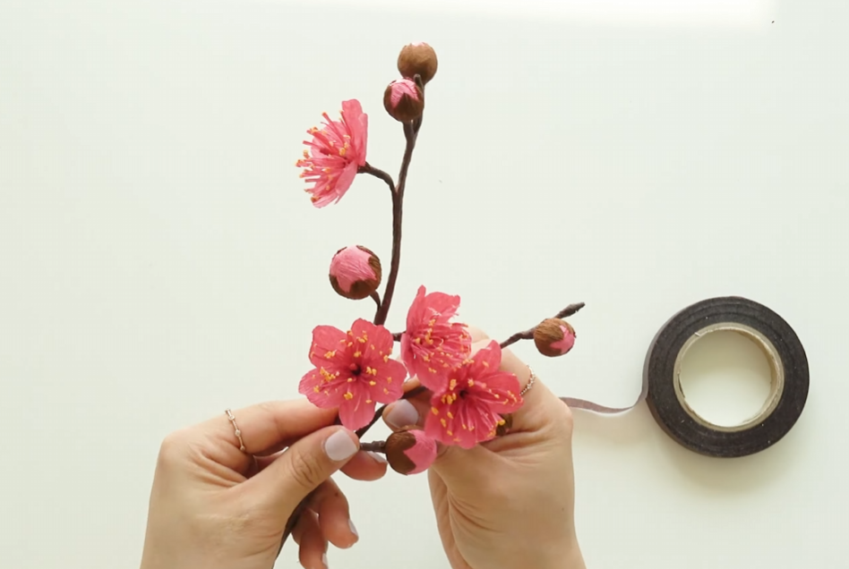Assembling crepe paper plum blossoms and buds into a finished branch