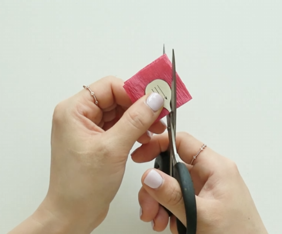 Cutting pink crepe paper petals using a plum blossom pattern