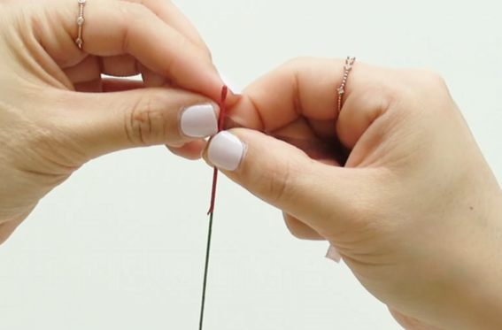 Wrapping red floral tape around floral wire for a paper plum blossom