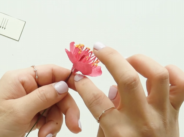 Attaching five pink crepe paper petals around the plum blossom center