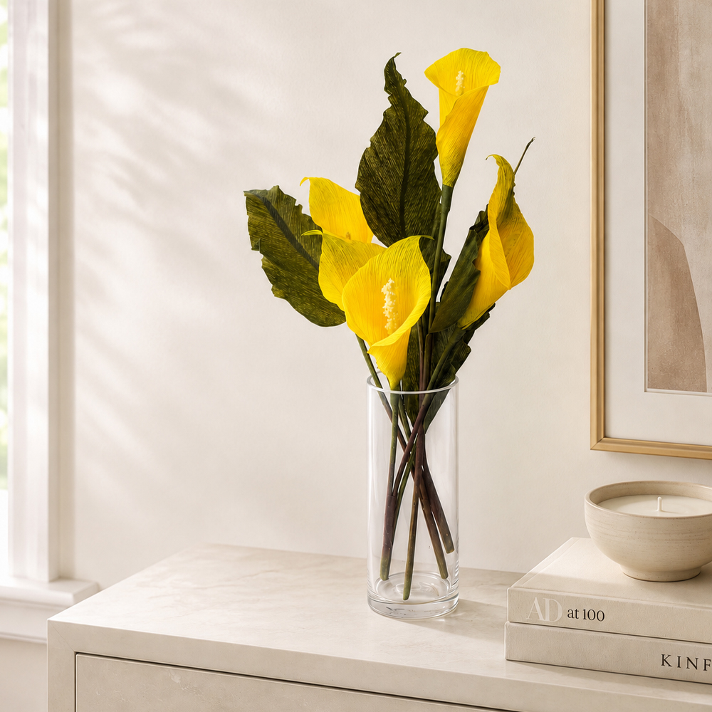 Handmade crepe paper calla lilies arranged naturally at different heights in a clear glass vase
