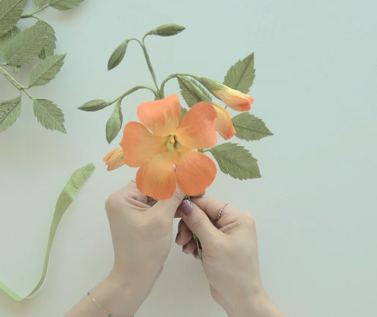 Connecting crepe paper trumpet vine flowers and leaves to complete the floral vine