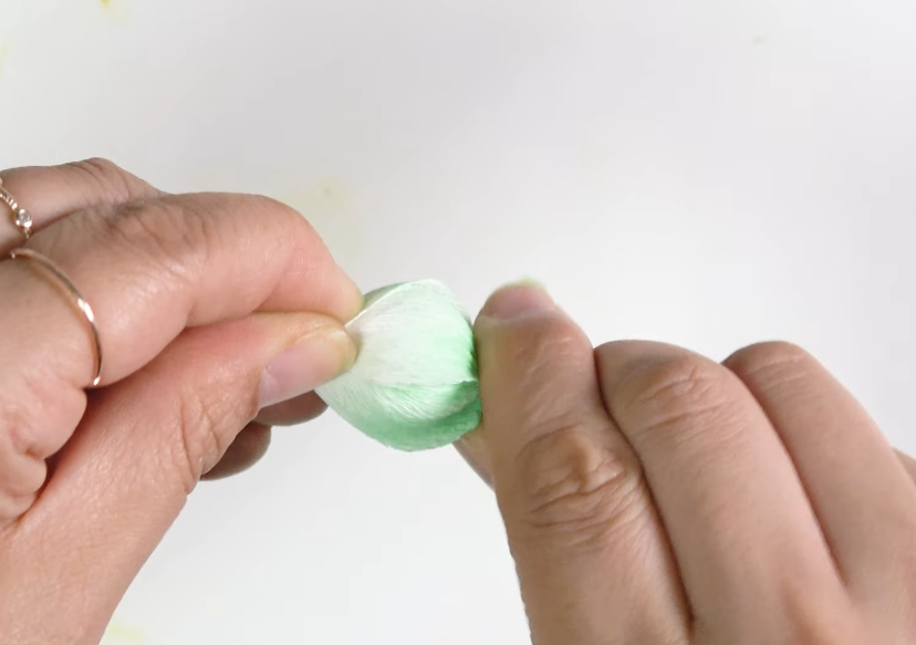 Attaching the green crepe paper calyx around a white lisianthus flower bud