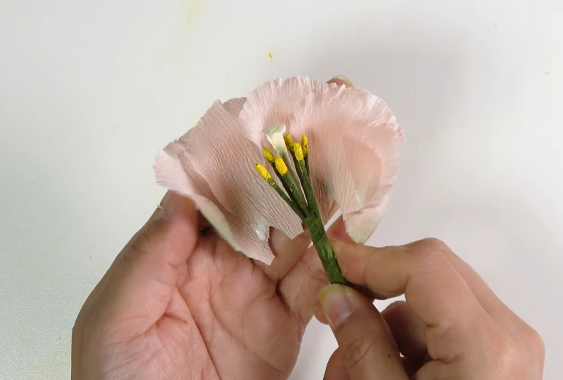 Applying glue to a crepe paper lisianthus petal before attaching it to the flower center