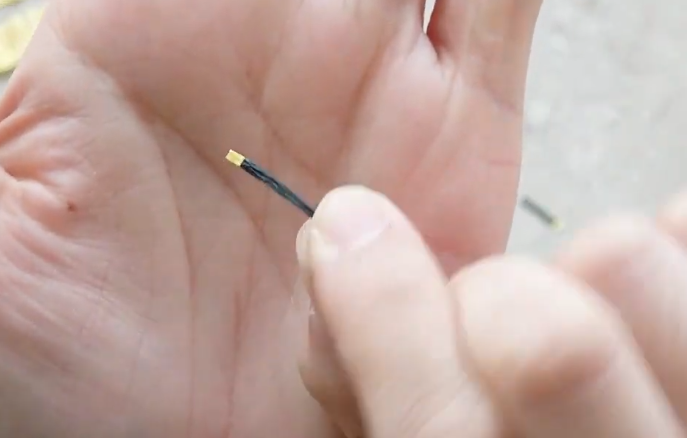 Folding and shaping a small black crepe paper stamen for a realistic cosmos center