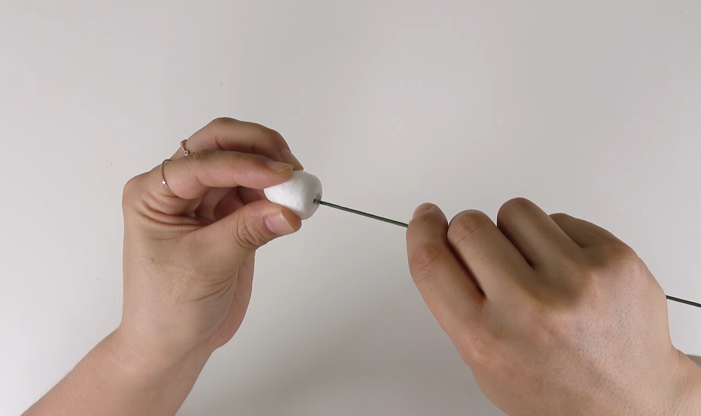 Inserting 18-gauge floral wire into a rosebud foam for a crepe paper rose
