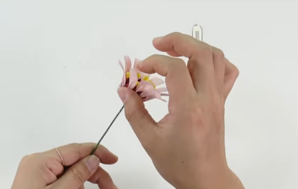 Attaching light pink crepe paper petals around the center of a handmade zinnia flower.