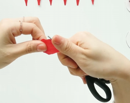 Shaping the edge of a red crepe paper petal by gently stretching and curling it