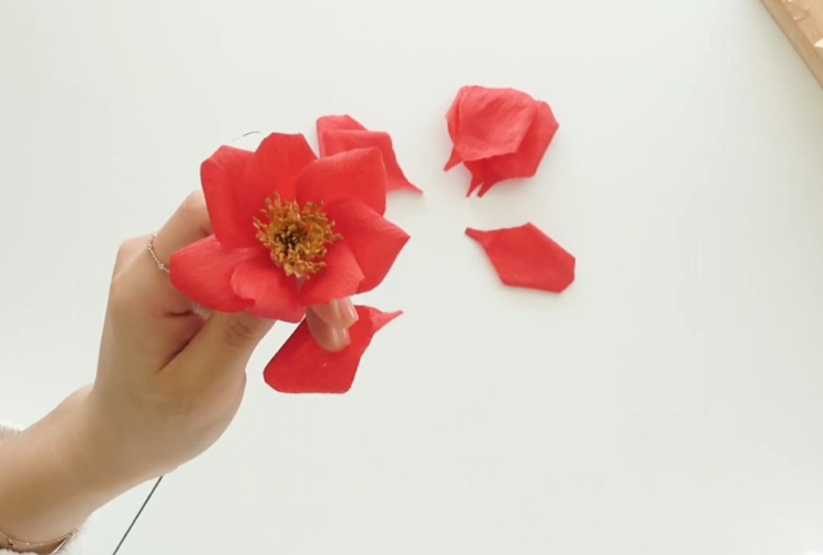 Attaching the first layer of red petals around the handmade rose center