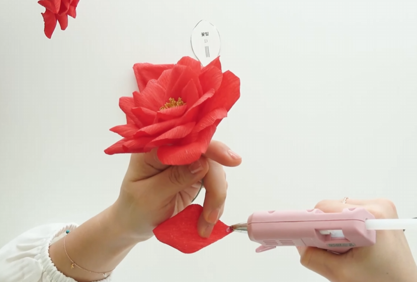Adding outer crepe paper petals with hot glue to build a full realistic paper rose