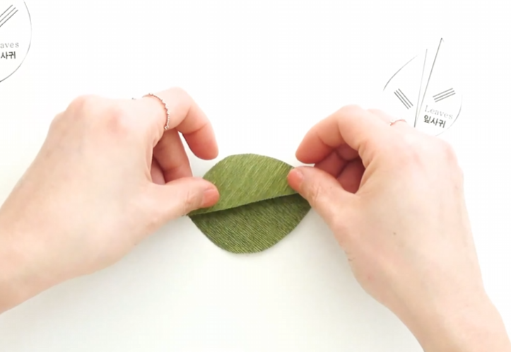 Joining two green crepe paper leaf halves around floral wire
