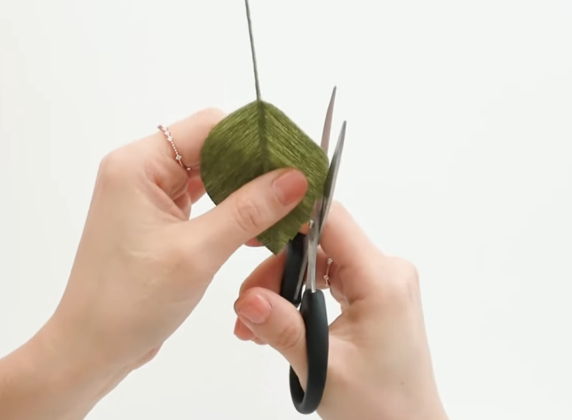 Cutting serrated edges into a wired crepe paper rose leaf for realistic detail