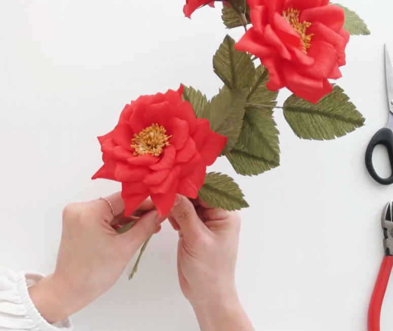 Connecting finished paper roses and green leaves to assemble the rose vine