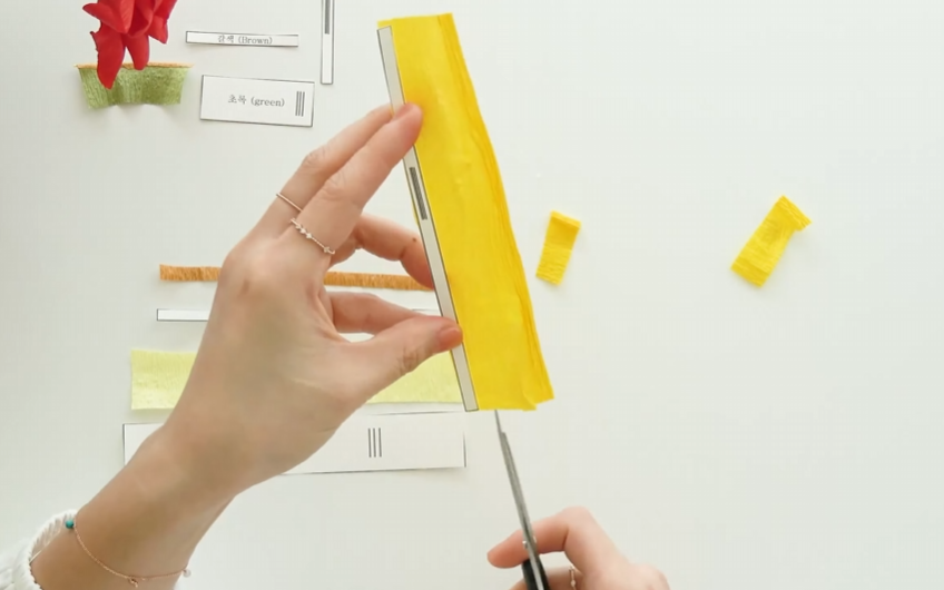 Trimming lemon yellow crepe paper to size using the paper flower pattern