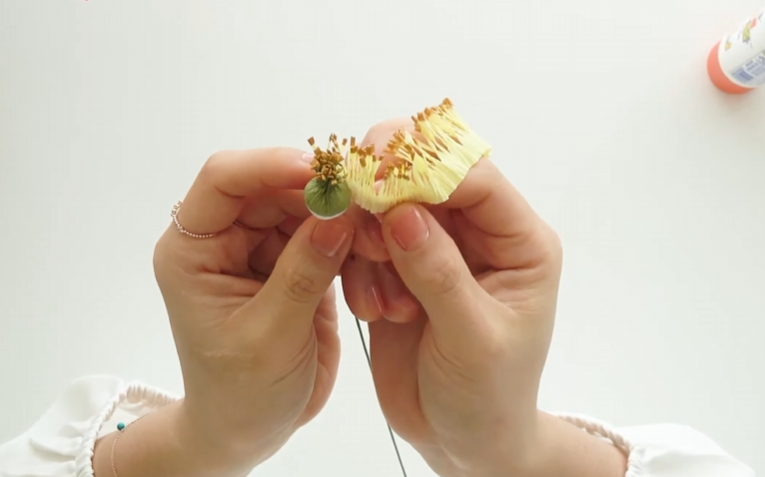 Wrapping yellow stamen around the prepared flower center for a crepe paper rose
