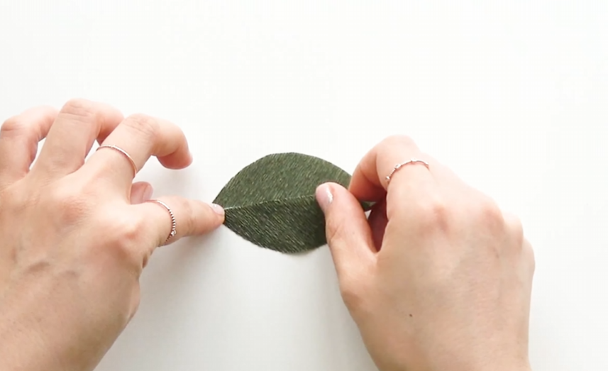 Attaching finished kumquat branches to a wooden branch for a handmade crepe paper garland
