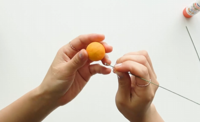 Wrapping a Styrofoam ball with yellow floral tape to make a kumquat fruit