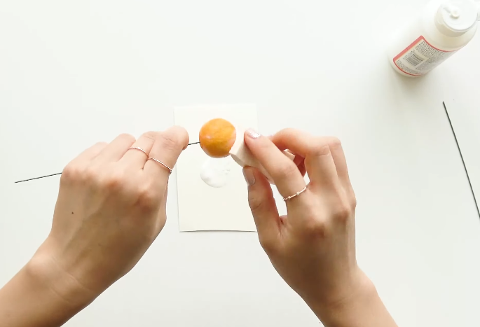 Adding orange pastel color to a handmade kumquat fruit with a sponge