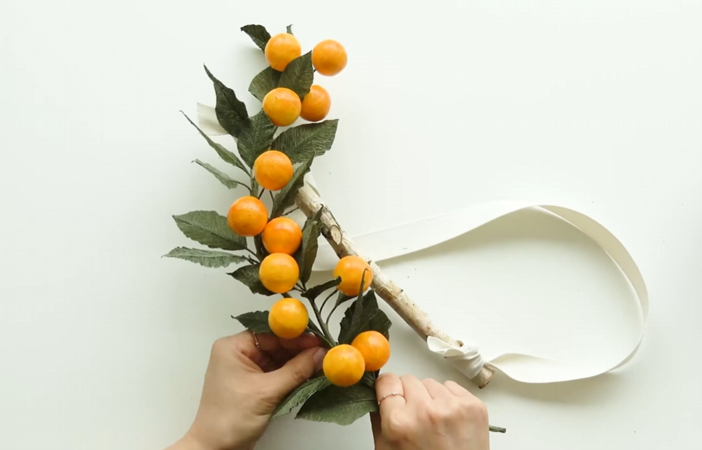 Applying gloss varnish to a handmade kumquat fruit for a realistic shiny finish