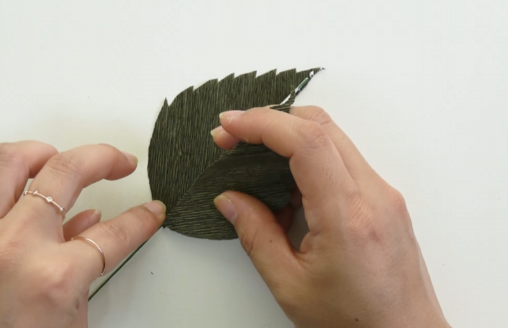 Gluing green floral wire between two crepe paper leaf layers for a tropical hibiscus flower