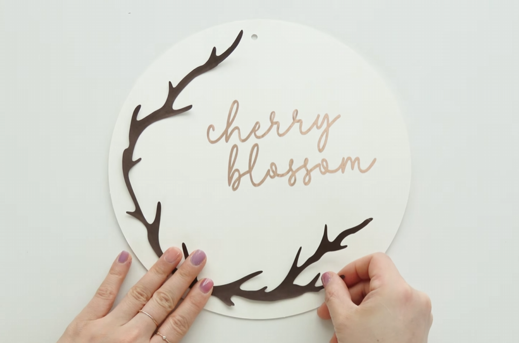 Attaching brown paper branch pieces around the edge of the cherry blossom wreath base