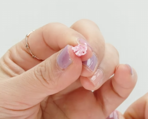 Rolling a pink paper stamen piece into a small flower center