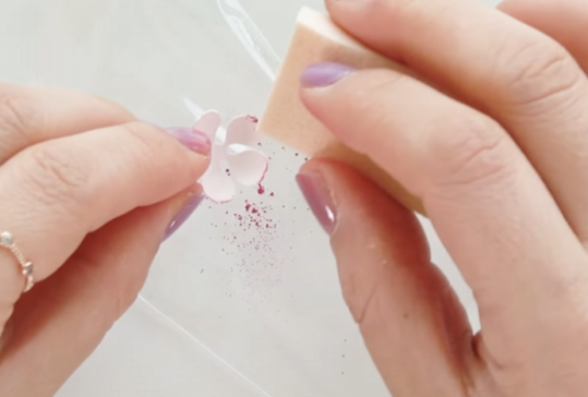 Applying pink pastel powder to the edges of paper cherry blossom petals