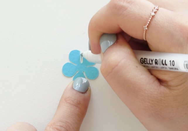 Adding white details to blue cardstock petals for forget-me-not paper flowers