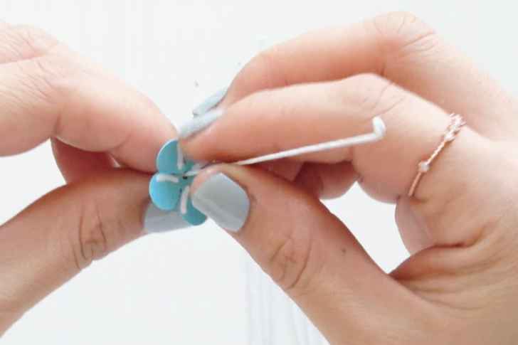 Inserting a looped 23-gauge wire through blue forget-me-not paper petals