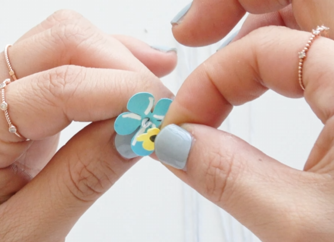 Attaching the yellow flower center to a blue forget-me-not paper flower