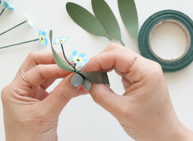 Wrapping forget-me-not flower stems and leaves together with green floral tape